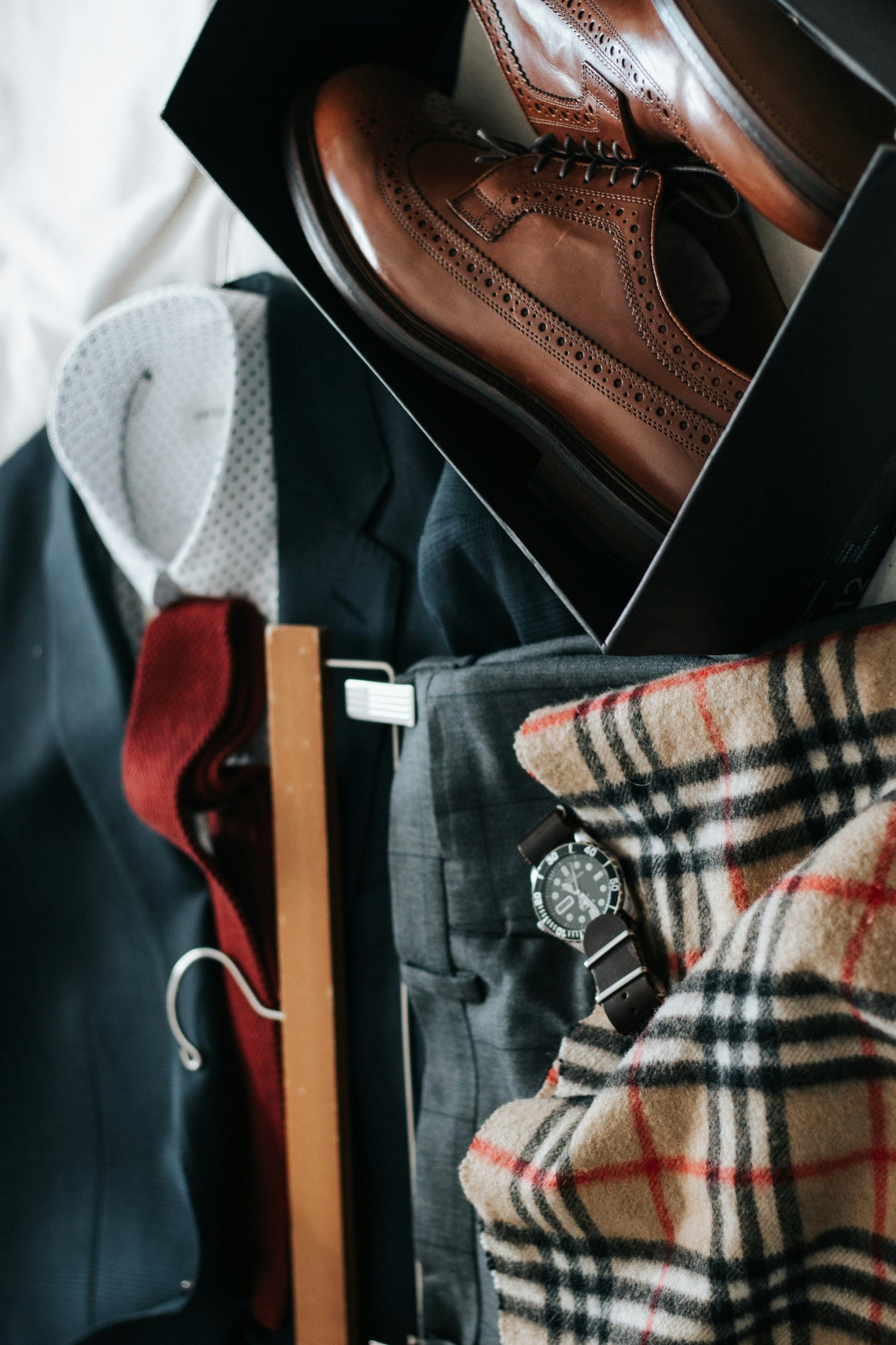 Collection of men's clothing and accessories including shoes, watch, and plaid fabric.
