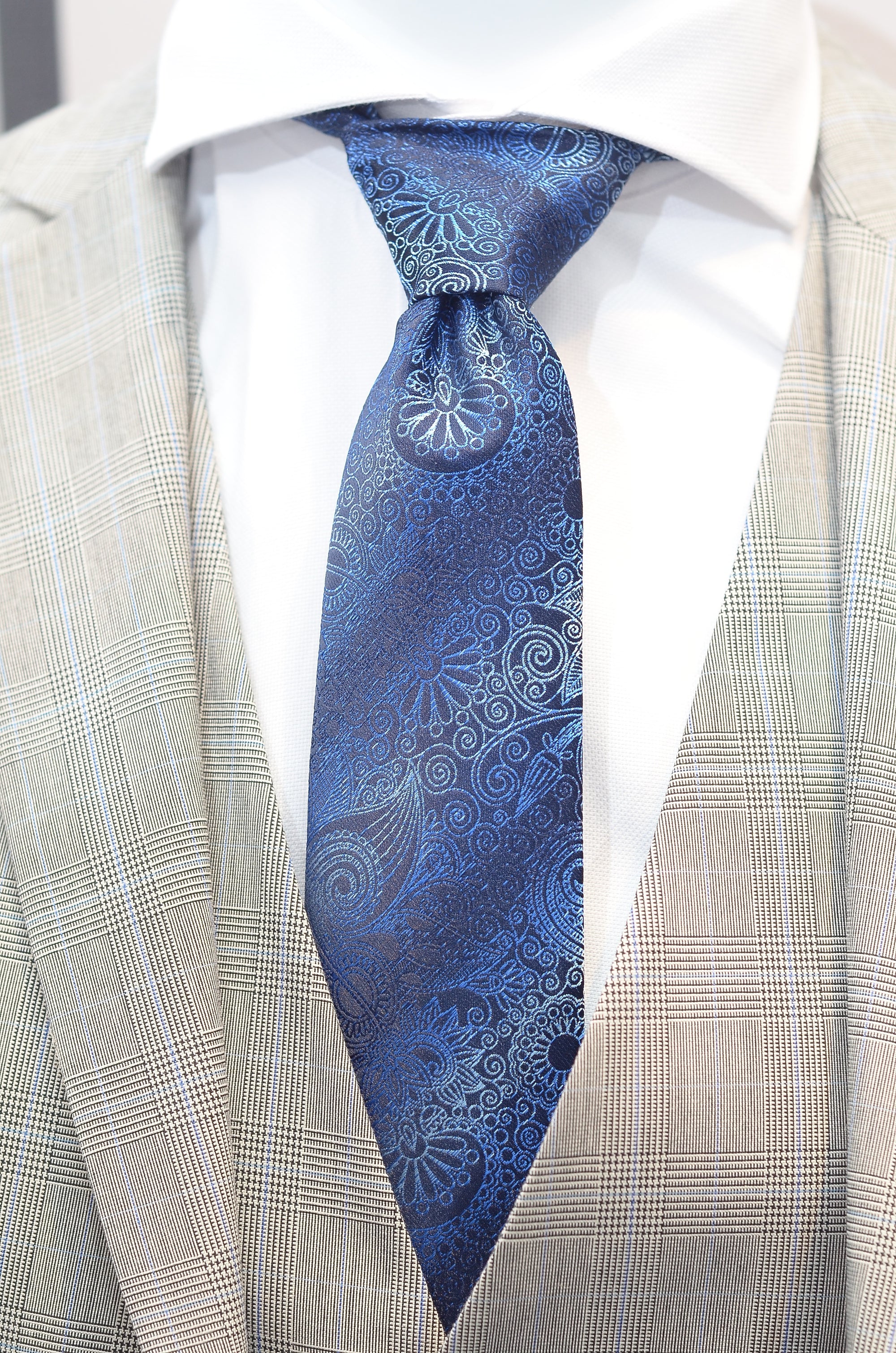 Blue paisley tie worn with a beige suit jacket