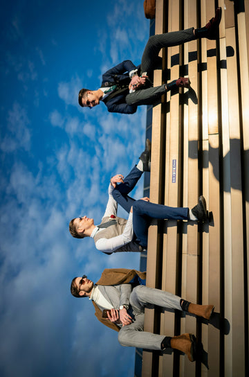Three men in suits sitting on steps against a blue sky